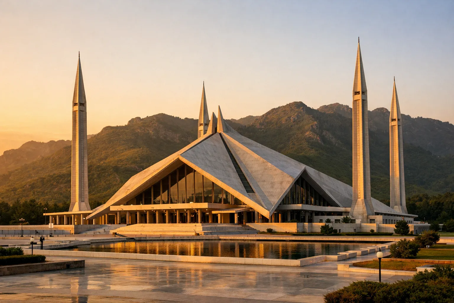 A modern triangular mosque silhouetted against the green Margalla Hills at golden hour.