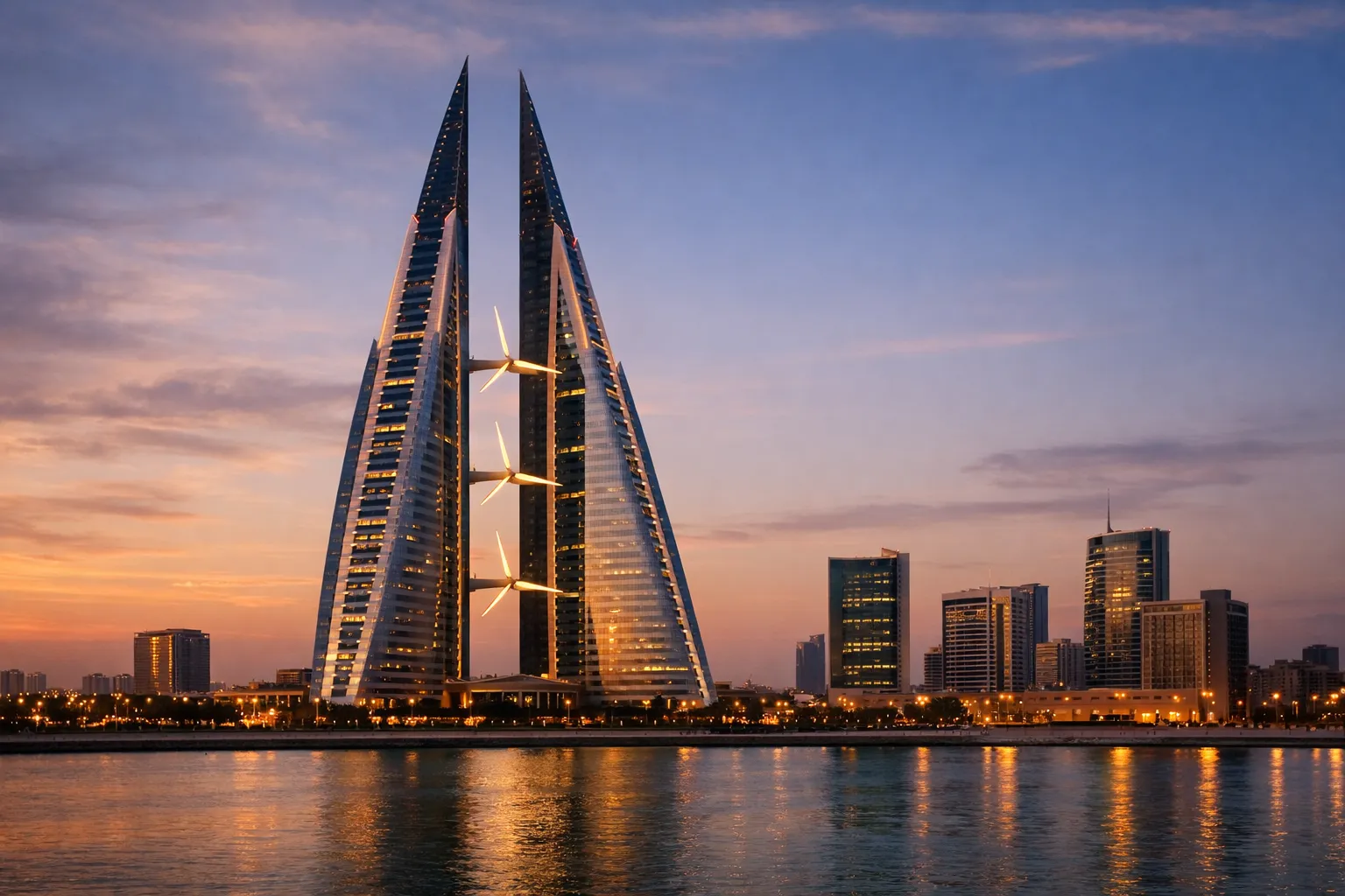 The twin sail-shaped Bahrain World Trade Center towers illuminated at dusk within the Manama skyline.