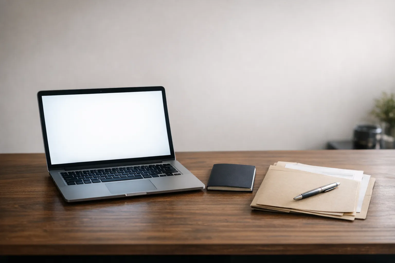 A laptop beside a passport and a visa appointment folder on a desk